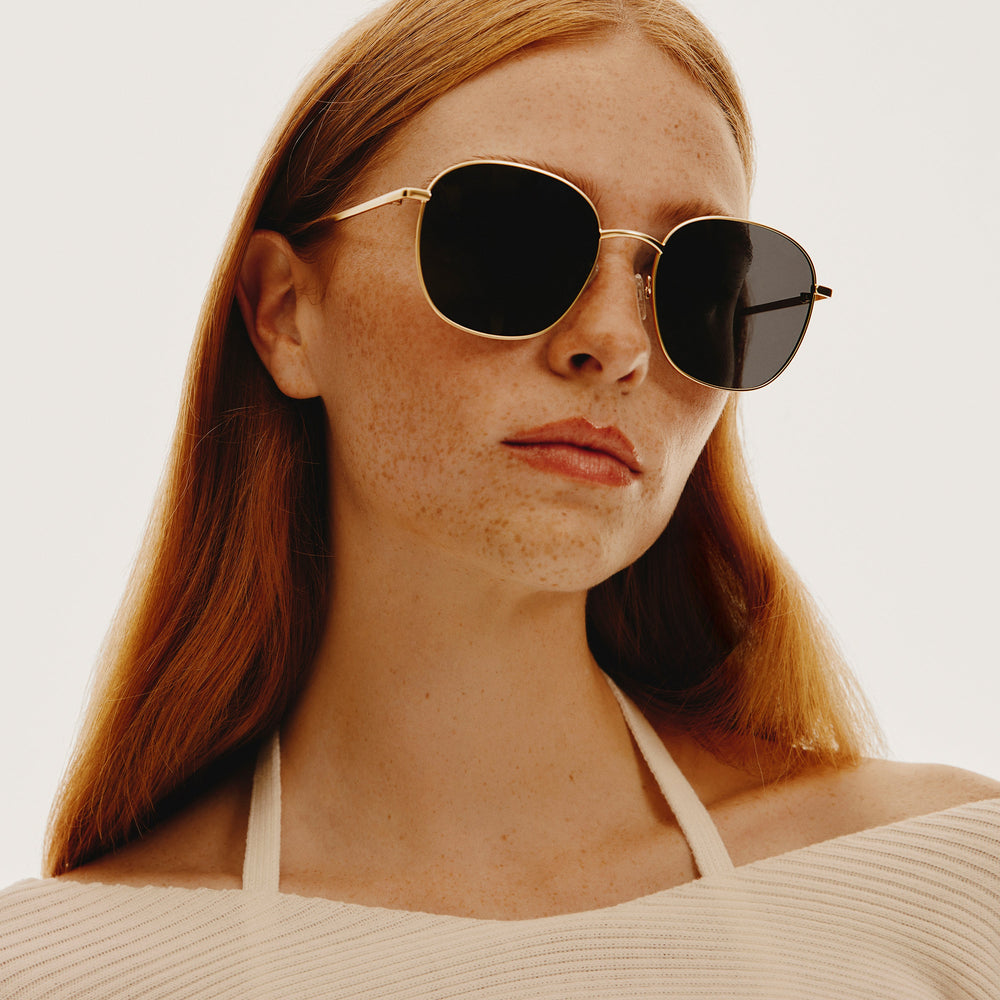 Model wearing QUAY JEZABELL gold metal frame round sunglasses for women